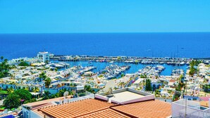 A marina with numerous boats docked, surrounded by residential buildings with visible satellite dishes. - Best View in Puerto de Mogán | Panoramic Terrace (Lomo Quiebre)