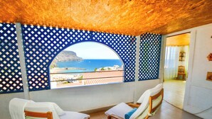 A room with two wooden chairs and a view of the sea through a blue lattice window. - Best View in Puerto de Mogán | Panoramic Terrace (Lomo Quiebre)