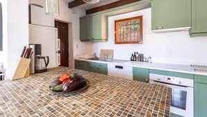 A kitchen with green cabinets, a tiled island, and a built-in oven. - Casa Vermella with Pool and Terrace (Sorède)