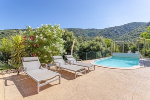 Ein Poolbereich mit Liegestühlen und Blick auf ein Gebirge.