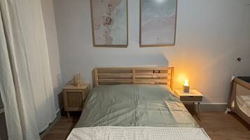 Un dormitorio con cama, dos mesitas de noche, una lámpara y una ventana con cortinas.