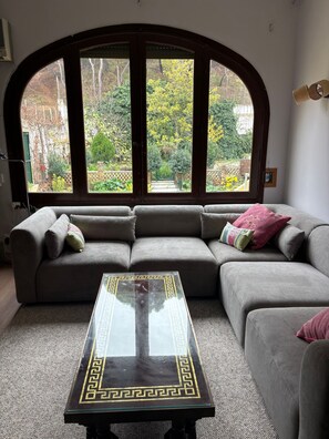 A living room with a sectional sofa, a glass coffee table, and a large arched window overlooking a garden. - House with Pool (June 15 - September 15) in Tudela-Bardenas (Tudela)