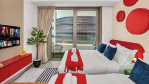 Moderni hotellihuone, jossa on suuri sänky, televisio, josta voi katsoa elokuvia, parveke, jolta avautuu näkymä moderniin rakennukseen, sekä punavalkoinen värimaailma.