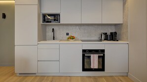 A modern kitchen with white cabinetry, a built-in microwave, a coffee maker, and a small oven. - Sublime AC Apartment Eiffel Tower Champs de Mars (Paris)