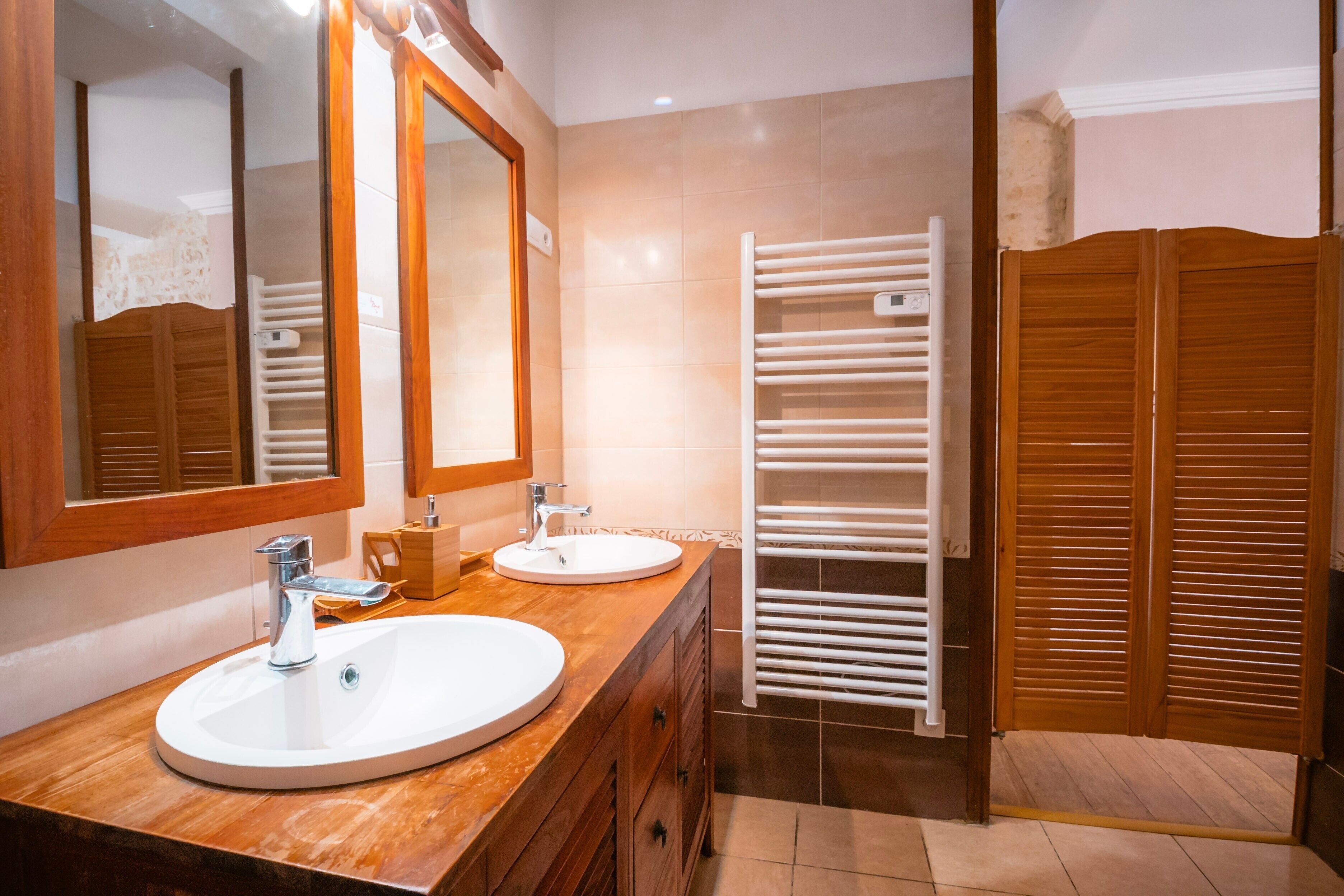 A bathroom with two sinks, a mirror, and a towel rack.