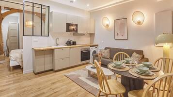 Een ruimtelijke leefruimte met kitchenette, eethoek en zithoek.