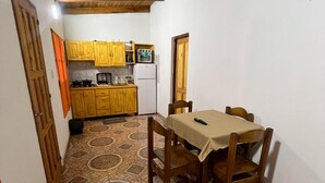 A compact kitchen with wooden cabinets, a dining table, and a patterned tile floor. - Bay cabins (Puerto Iguazú)