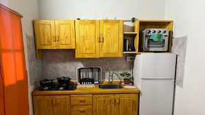 A compact kitchen with wooden cabinets, a built-in microwave, a stove, and a refrigerator. - Bay cabins (Puerto Iguazú)