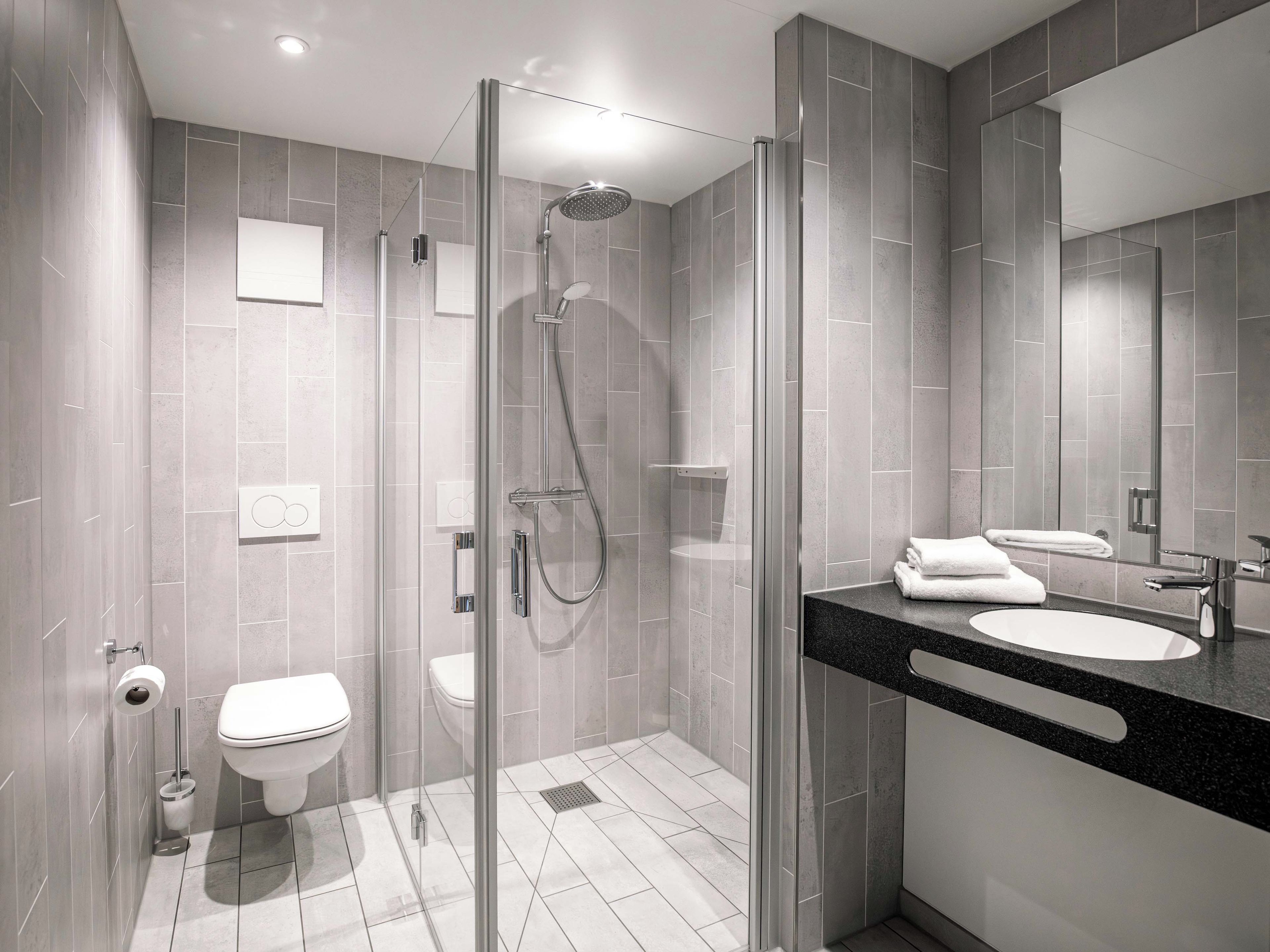 Ein modernes Badezimmer mit einer Duschkabine, einer Toilette und einem Waschbecken mit schwarzer Arbeitsplatte.