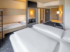 Habitación de hotel con dos camas, un escritorio, una silla, un televisor y un espejo.