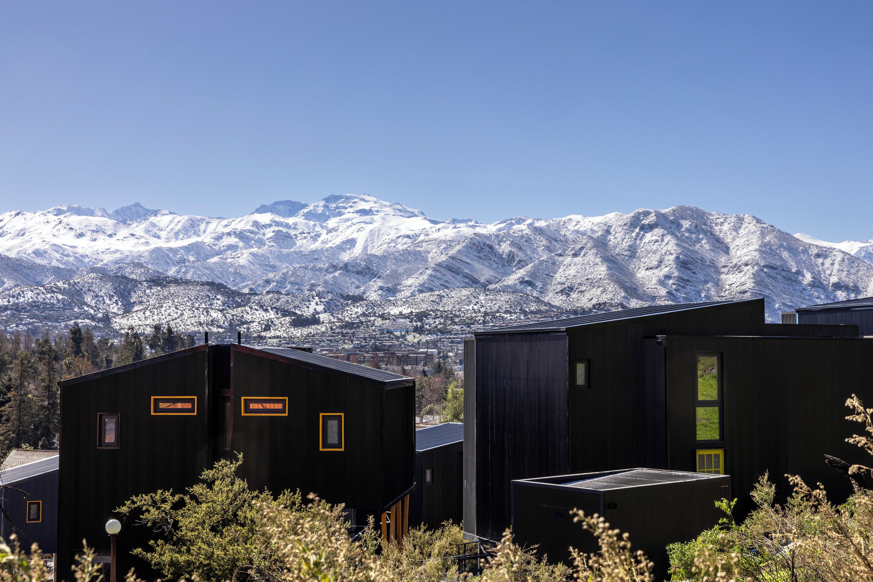A modern building with a mountain backdrop, featuring a prominent entrance and a visible staircase.