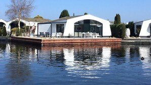 A modern houseboat with a covered deck, outdoor seating, and a view of the water. - Suny bungalow with a private jetty. (Lemmer)