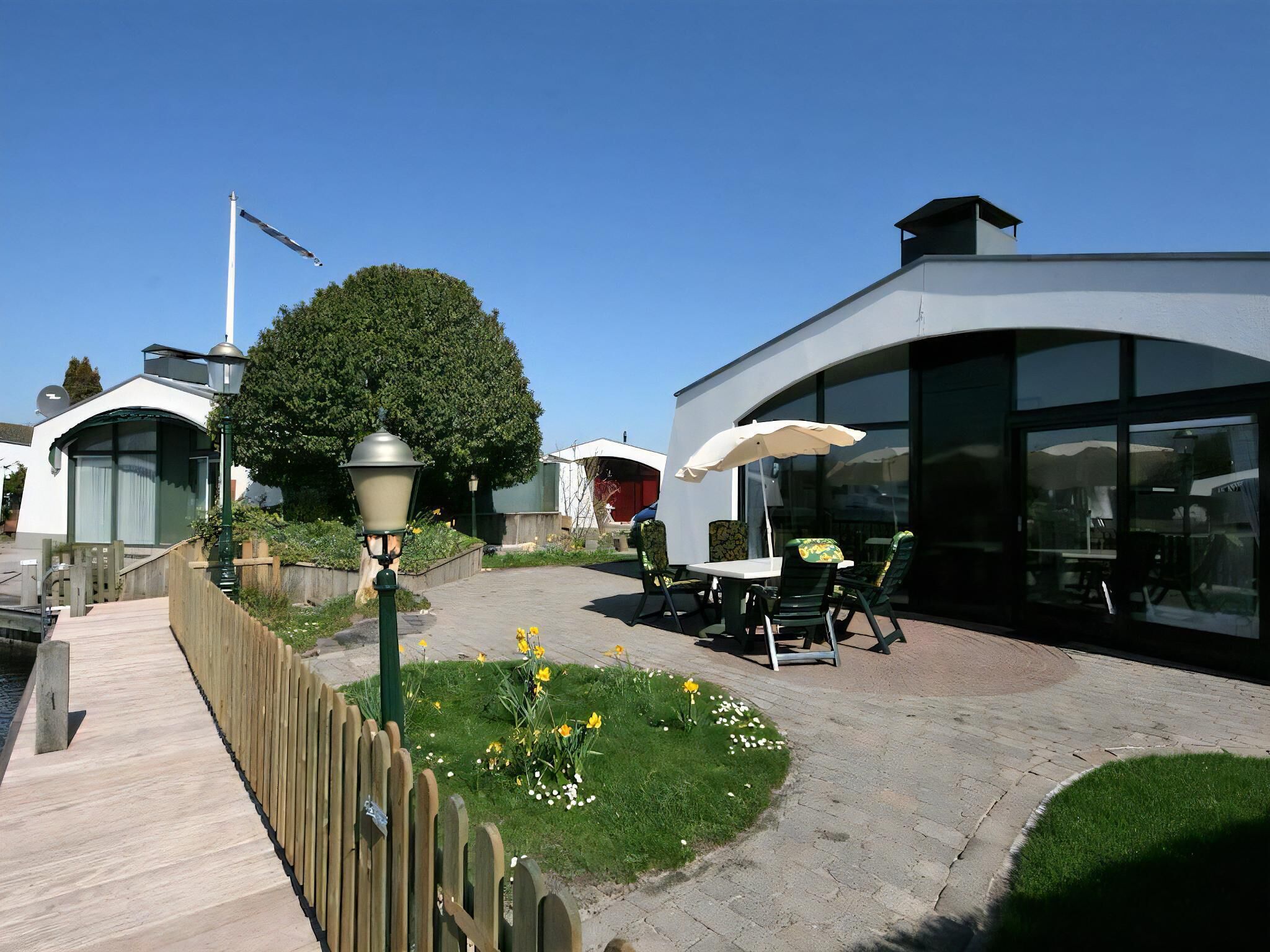 A patio area with outdoor seating, a lamp post, and a pathway leading to a building with large windows.