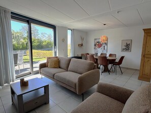 A modern living room with a sofa, coffee table, and dining area with chairs. - Park Brekkense Wiel 190 (Lemmer)