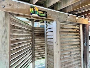 A wooden structure with slatted walls and a sign indicating showers. - Bailey Beach House Beach Views (Freeport)