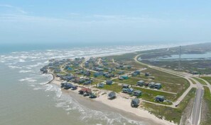 An aerial view of a coastal residential area with houses along the beachfront and a road curving through the landscape. - Bailey Beach House Beach Views (Freeport)