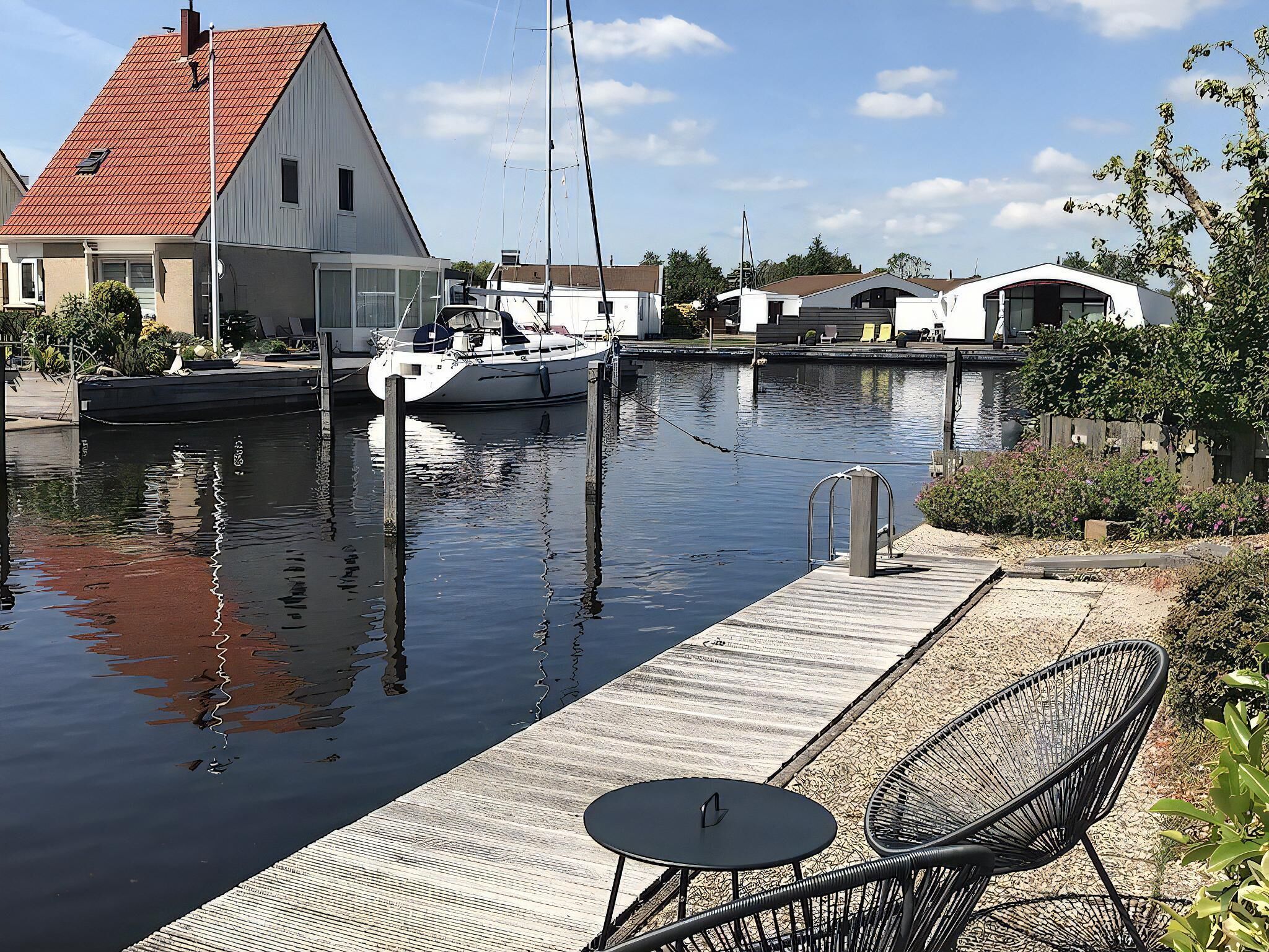 A marina with a dock, a small boat, and a house with a red roof.