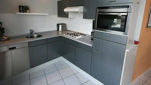 Una cocina moderna con armarios grises, un lavamanos de acero inoxidable y un horno empotrado.