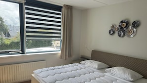 A bedroom with a bed, a window with blinds, a radiator, and wall decor. - Park Brekkense Wiel 173 (Lemmer)