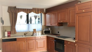 A compact kitchen with wooden cabinets, a microwave, a sink, and a dishwasher. - Park Brekkense Wiel 173 (Lemmer)