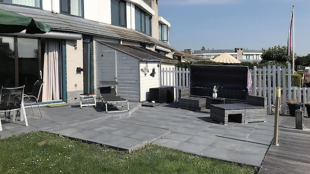 A modern house with a patio area featuring outdoor furniture, a barbecue setup, and a white picket fence. - Park Brekkense Wiel 173 (Lemmer)