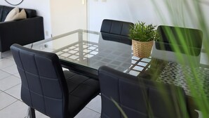 A modern dining area with a glass table, black chairs, and a woven plant pot.