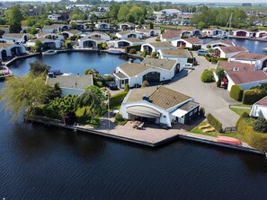 Eine Marina mit modernen, weißen Häusern mit geneigten Dächern, verbunden durch Wege, und einer Anlegestelle mit einem roten Boot.