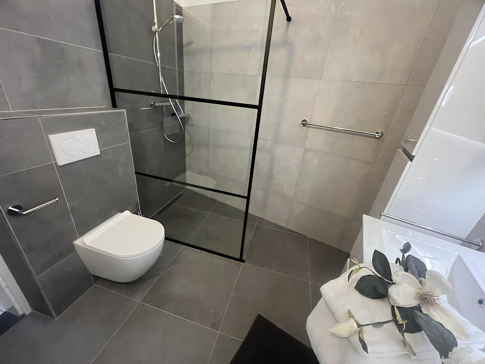Um banheiro moderno com chuveiro em cabine de vidro, vaso sanitário e banheira.