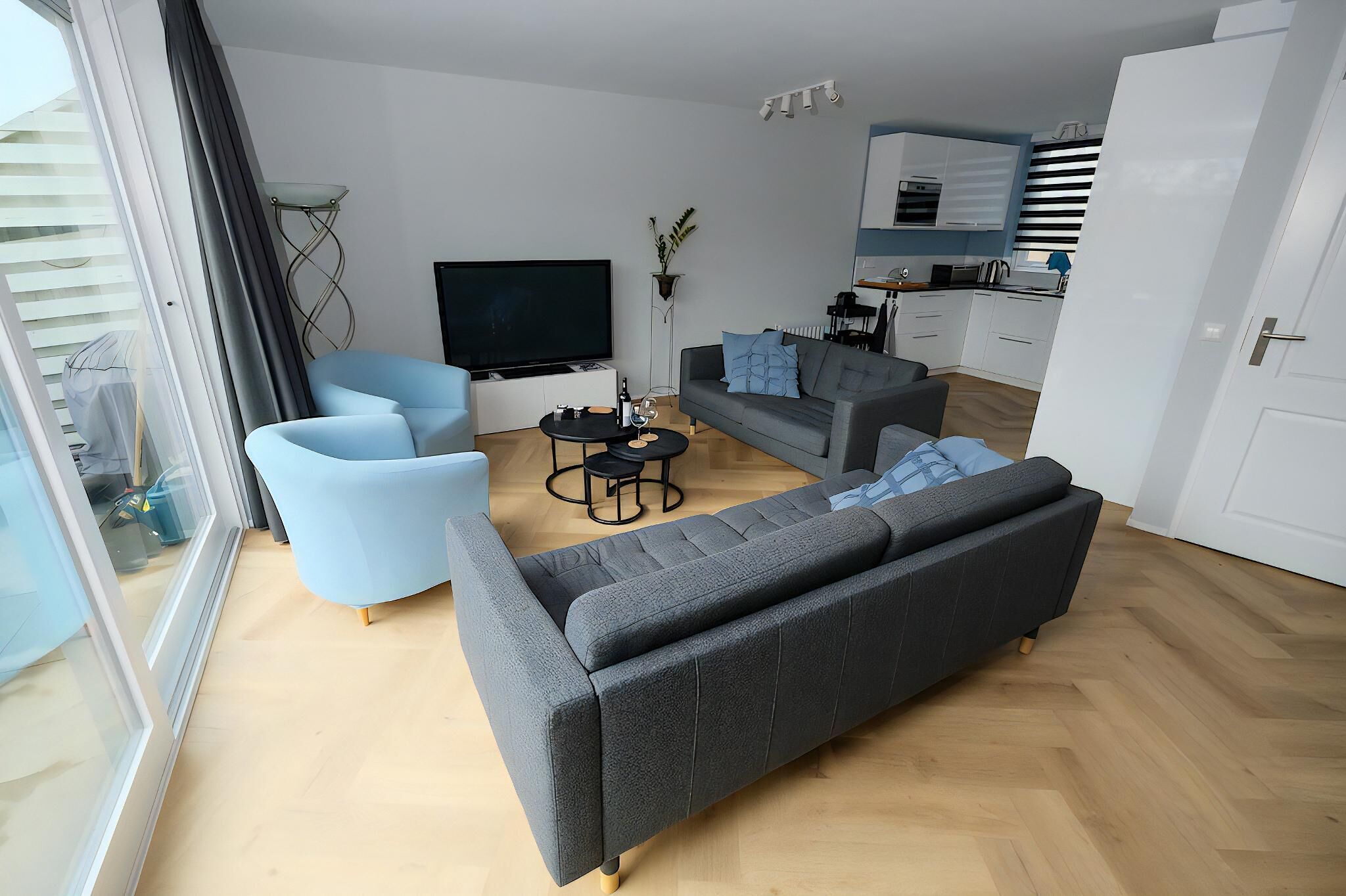 En moderne stue med en grå sofa, en blå lænestol og et lille sofabord.