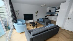 A modern living room with a grey sofa, a blue armchair, and a small coffee table. - Park Brekkense Wiel 103 (Lemmer)
