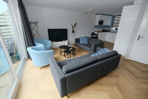 A modern living room with a grey sofa, a blue armchair, and a small coffee table. - Park Brekkense Wiel 103 (Lemmer)