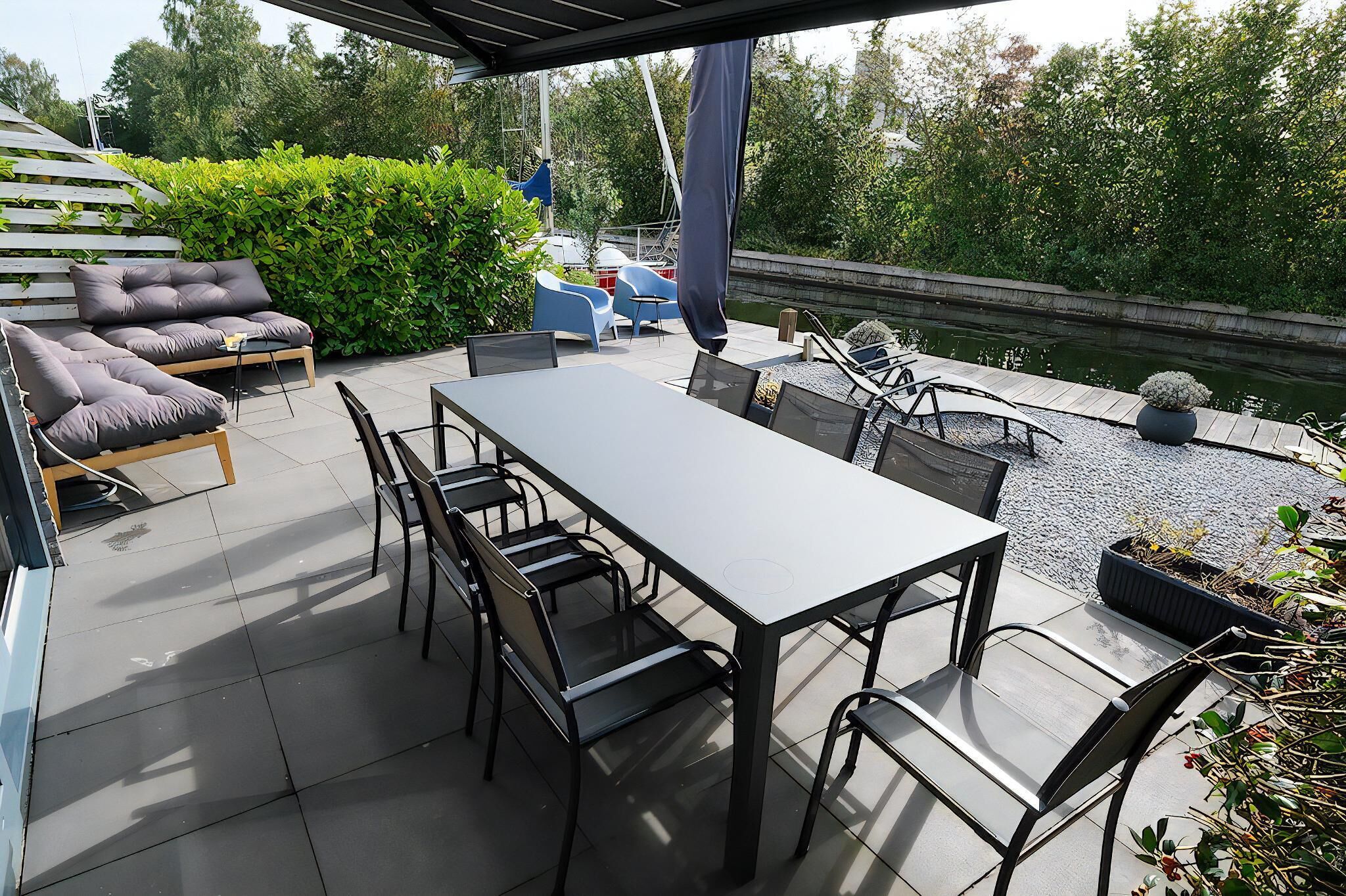 Une terrasse extérieure avec une table et des chaises, un canapé et un petit espace de jeux équipé d’un toboggan.