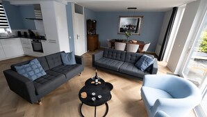 A modern living room with two sofas, a coffee table, and a dining area with a table and chairs. - Park Brekkense Wiel 103 (Lemmer)