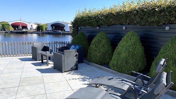 A patio with outdoor seating, a water body, and a hedge. - Bungalow at the waterside pets friendly (Lemmer)