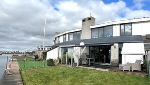 Une maison moderne dotée d’un patio couvert, d’une pelouse et d’une vue sur la rivière.