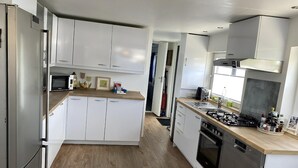 A modern kitchen with white cabinets, a microwave, a gas stove, and a dishwasher.