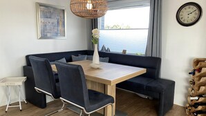 A modern dining area with a wooden table, black upholstered chairs, and a blue sofa.