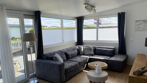 A modern living room with a sectional sofa, a small round table, and a lamp.