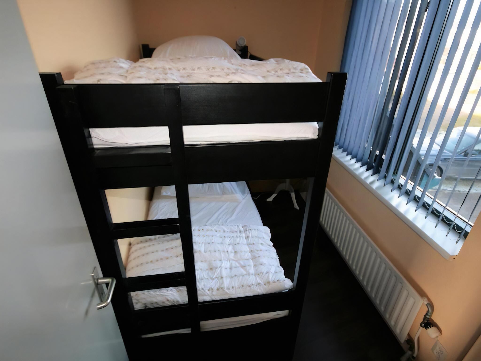 Ein Stockbett mit Blick aus dem Fenster, einem Heizkörper und einer Tür.