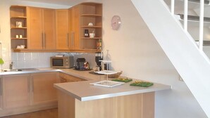 A modern kitchen with wooden cabinets, a microwave, a coffee maker, and a clock on the wall. - Park De Markol River House (Lemmer)