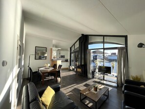 Ein modernes Wohnzimmer mit einer Couch, einem Couchtisch und Blick auf die Stadt durch große Fenster.