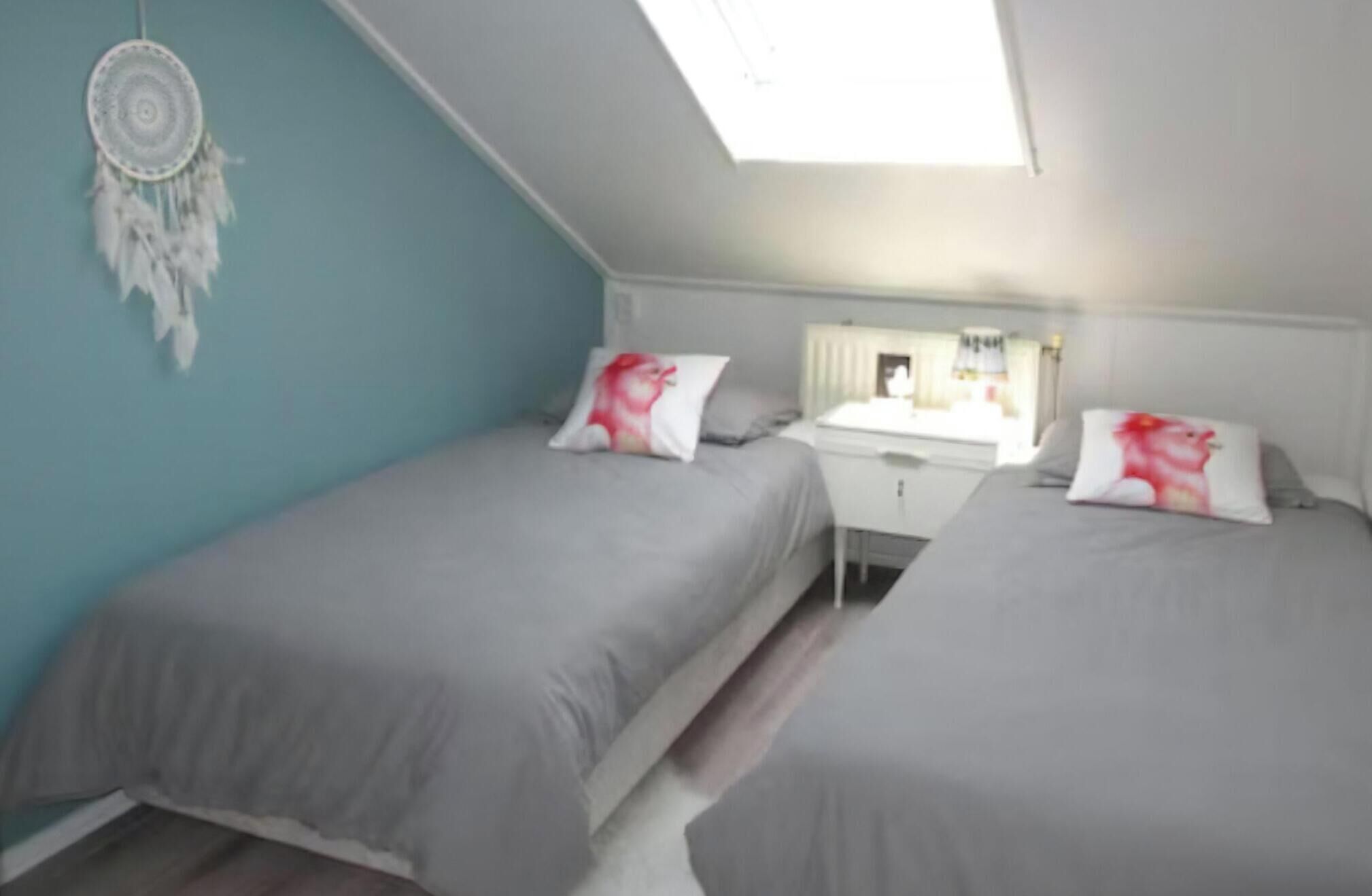 Een slaapkamer met twee bedden, een bureau en een dakraam.