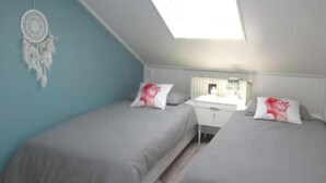 Une chambre avec deux lits, un bureau et une fenêtre de toit.
