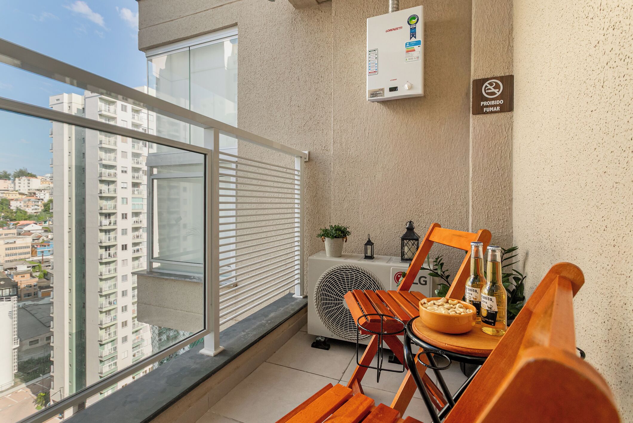 Un balcón con una mesa, sillas, un ventilador y vistas a la ciudad.
