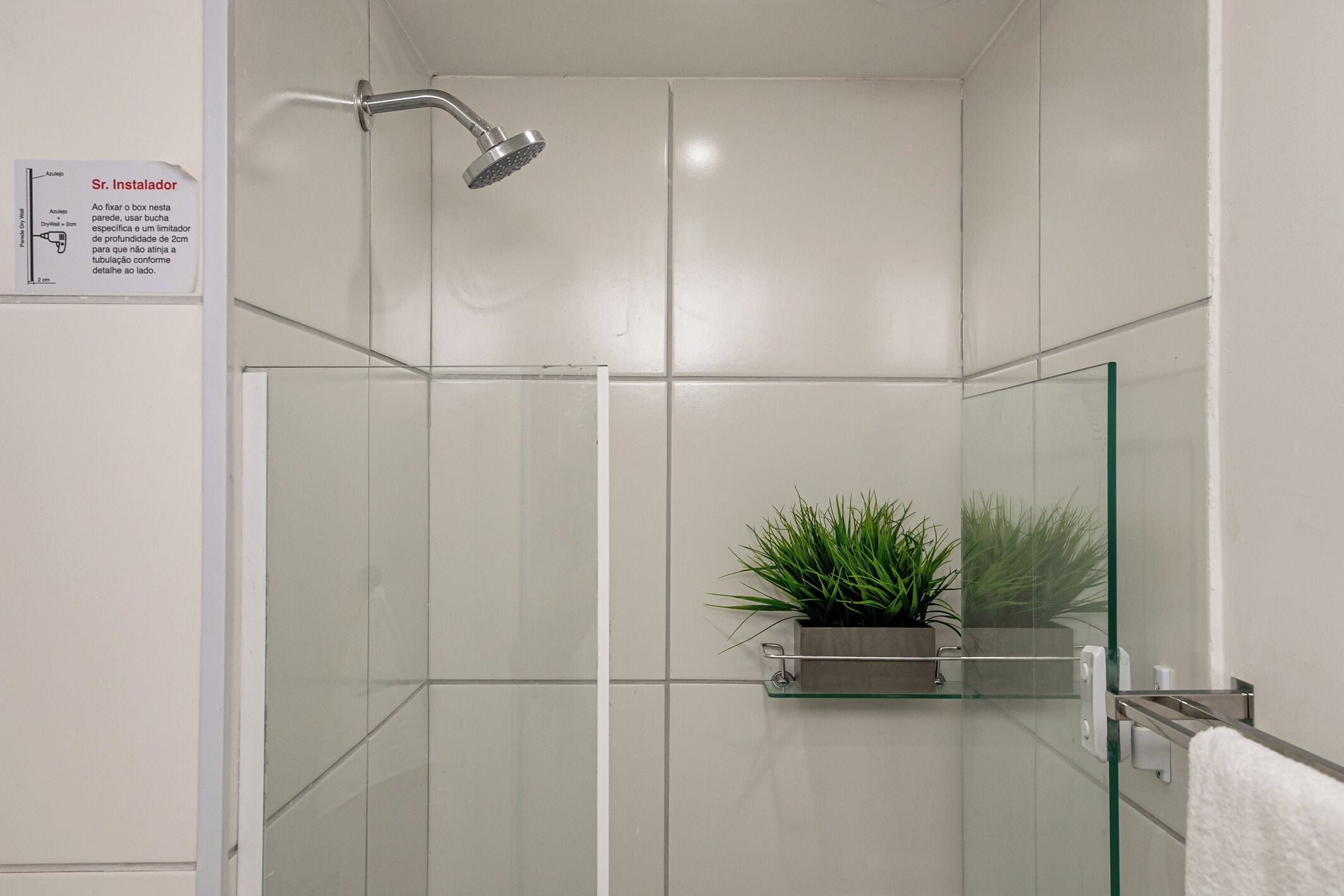 Een moderne badkamer met een douchecabine van glas, een potplant en een handdoekrek.