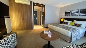 A hotel room with a bed, a small table, a sofa, and a wardrobe. - Astra Studio (Vevey)