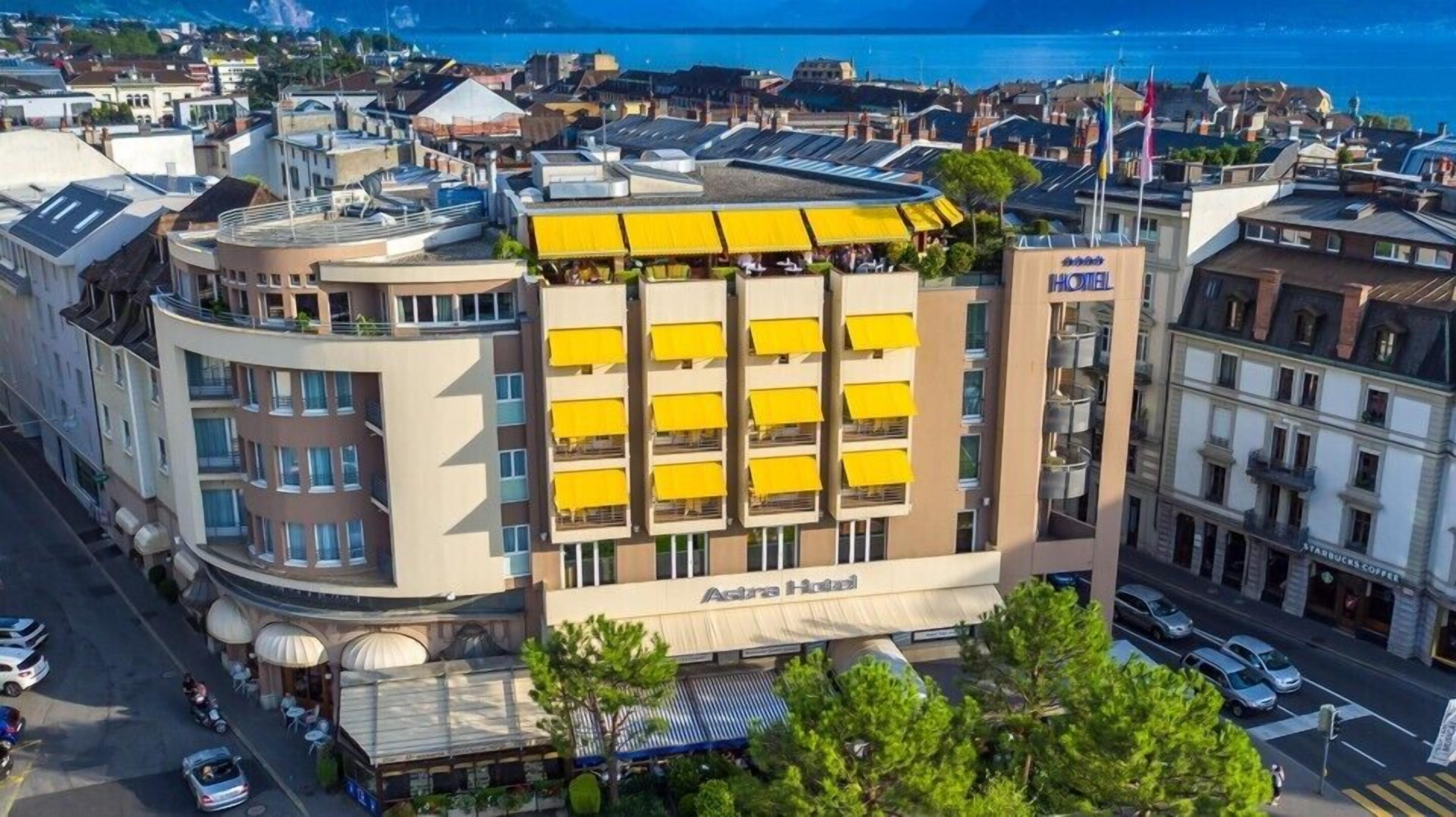 Ein mehrstöckiges Hotel mit einer auffälligen gelben Fassade, Balkonen und Blick auf das Meer.