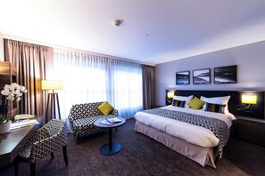 A hotel room with a bed, a desk with a lamp, a chair, and a small table. - Astra Studio (Vevey)