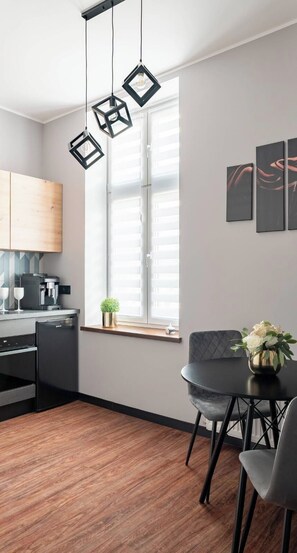 Cocina moderna con comedor, que incluye un refrigerador negro, una cafetera y una ventana con persianas.
