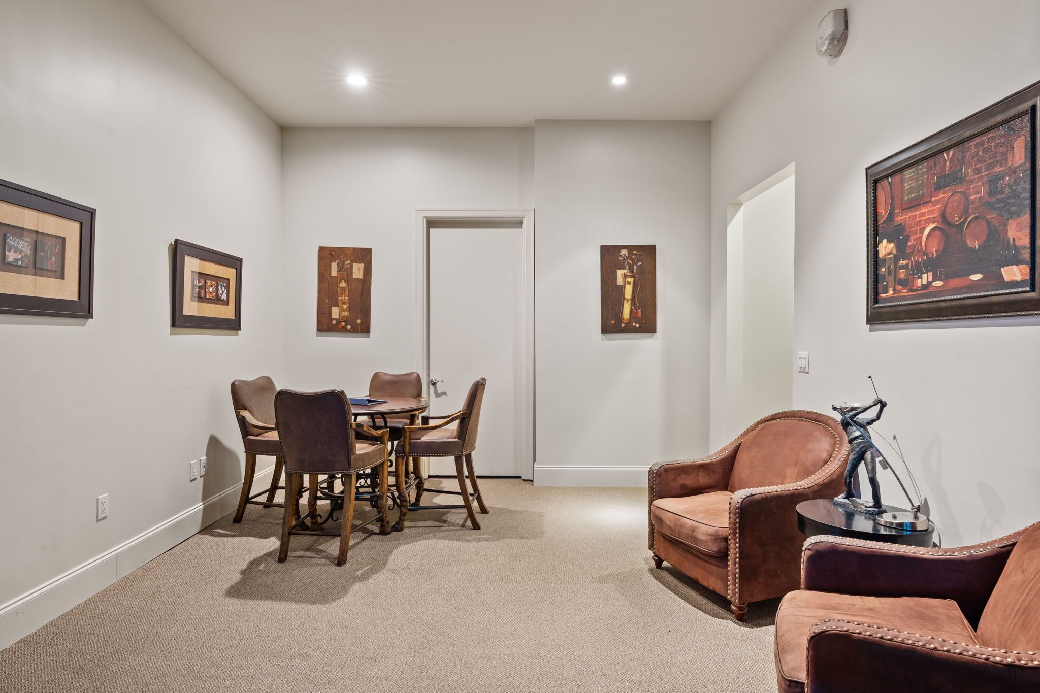 A room with a dining table and chairs, a sofa, and framed artwork on the walls.
